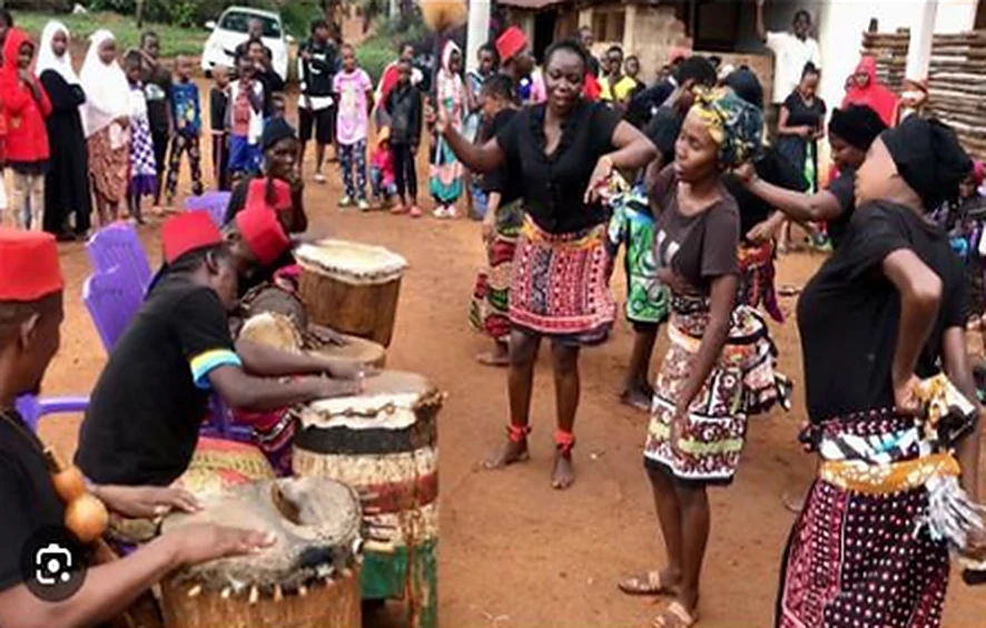 Community members dancing to drums during a traditional performance.